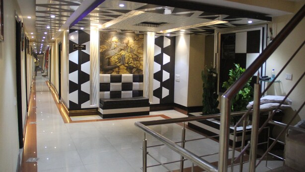 A hotel lobby with a checkered floor pattern, a staircase, and a wall with a geometric design. - hotel vikrant (Ludhiana)