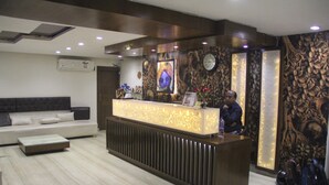 A reception area with a modern reception desk, a sofa, and a decorative wall. - hotel vikrant (Ludhiana)