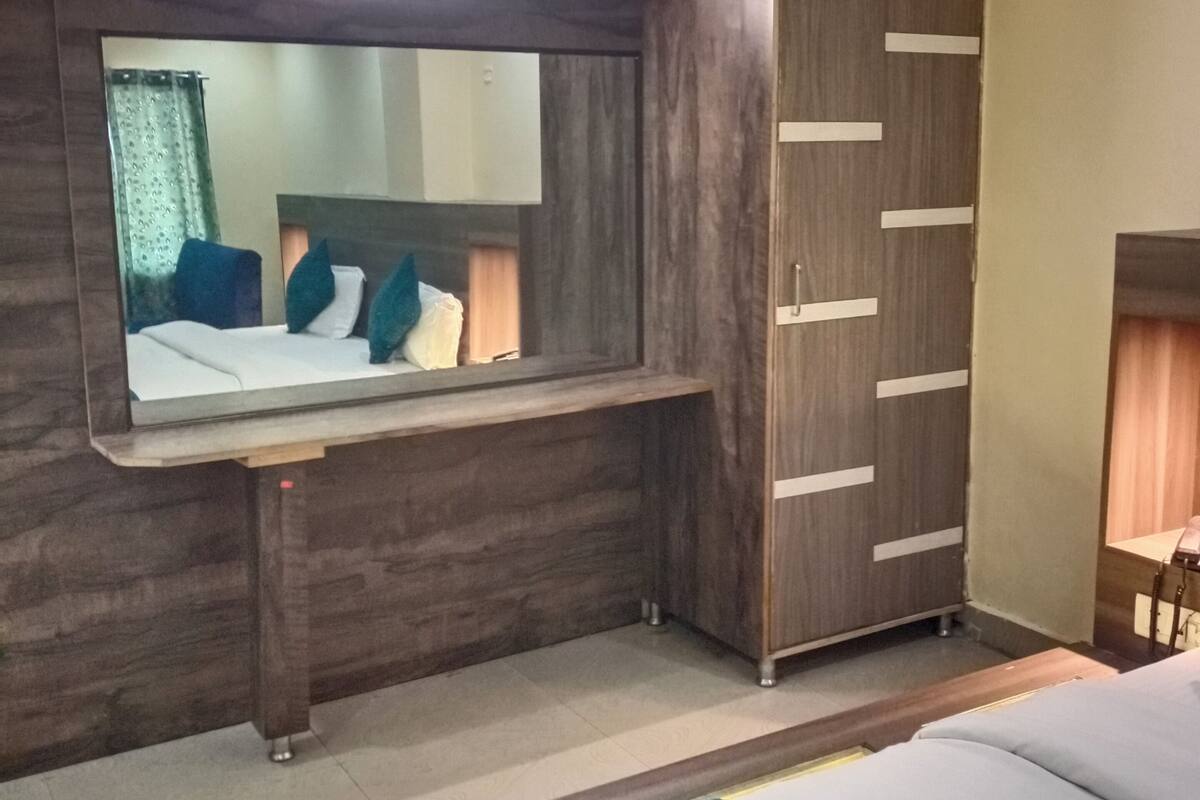 A hotel room with a bed, a wardrobe, a mirror, and a small desk.