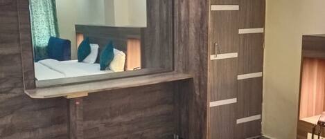 A hotel room with a bed, a wardrobe, a mirror, and a small desk.