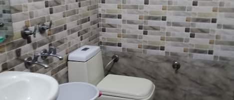 Un baño con inodoro, lavamanos y un bote de basura.
