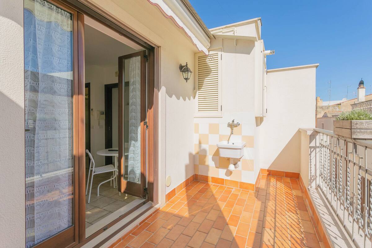 A balcony with a checkered floor, a white sink, and a door leading to an interior space.