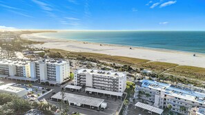 Un hotel fronte spiaggia con diversi edifici, parcheggi e una spiaggia sullo sfondo.