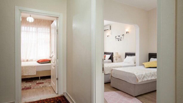 A bedroom with two beds, a sitting area with a bench, and a door leading to another room. - Convenient 3-Bedroom flat for 10, Near Blue Mosque, AC & WiFi (Istanbul)
