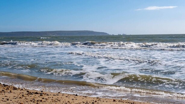 A beach with waves, pebbles, and a distant shoreline. - Railway Terrace by NewFo rest (Brockenhurst)