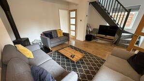 A modern living room with a grey sofa, a wooden coffee table, and a black and white patterned rug. - Railway Terrace by NewFo rest (Brockenhurst)