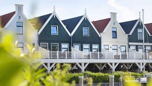 A row of traditional houses with steep gabled roofs and white railings, connected by a wooden bridge over a body of water. - Nice Apartment With Sauna, Near the Markermeer (Uitdam)