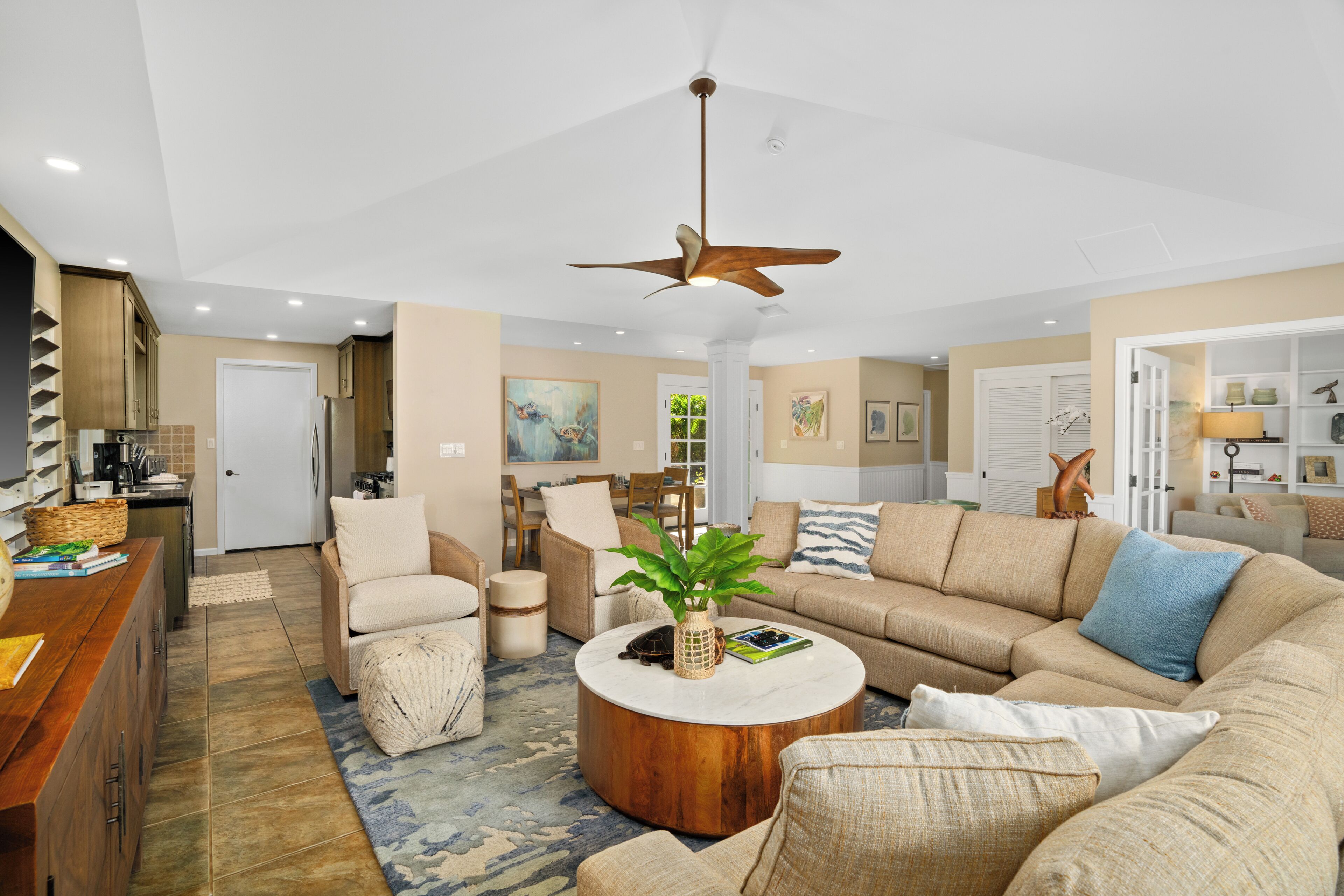 A spacious living room with a large sofa, a coffee table, and a ceiling fan.