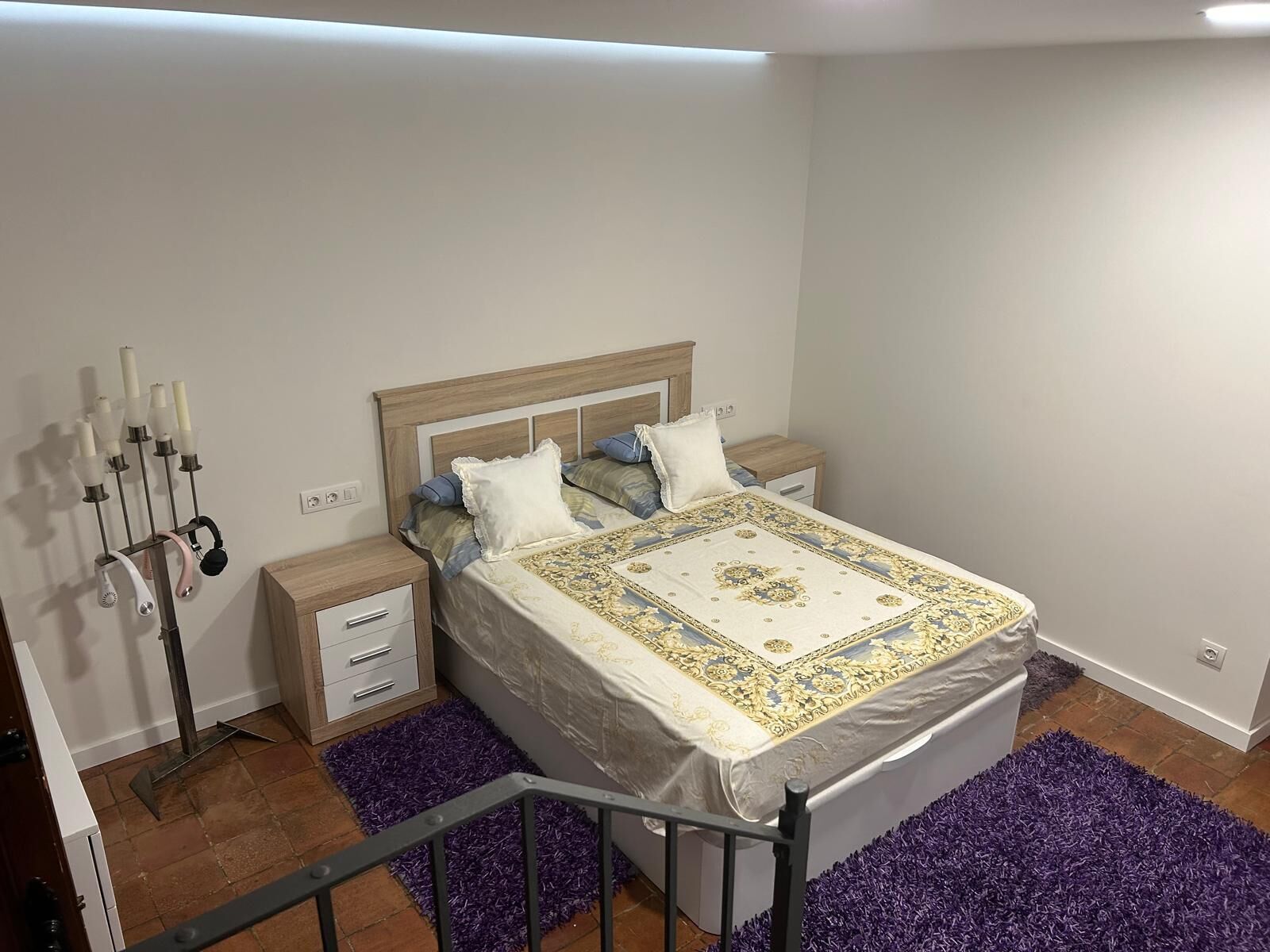 Een slaapkamer met een bed, twee nachtkastjes, een lamp en een wandlamp.