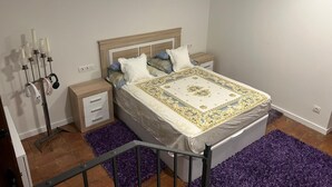 Een slaapkamer met een bed, twee nachtkastjes, een lamp en een wandlamp.