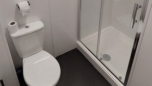 A modern bathroom with a toilet, a glass-enclosed shower, and a bathtub. - The Cotteridge Inn (Birmingham)