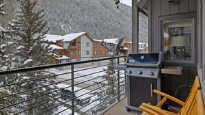 A balcony with a grill, a chair, and a view of snow-covered buildings and a mountain. - Owl Meadows-Curate Telluride-Fireplace, Views, Dog OK, Near Market, Lift 7 (Telluride)