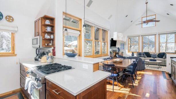 A spacious kitchen with a large island, wooden cabinets, and a dining area with a sofa and chairs. - Owl Meadows-Curate Telluride-Fireplace, Views, Dog OK, Near Market, Lift 7 (Telluride)
