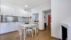 Une cuisine moderne avec des meubles blancs, une table à manger avec des chaises et une cheminée.