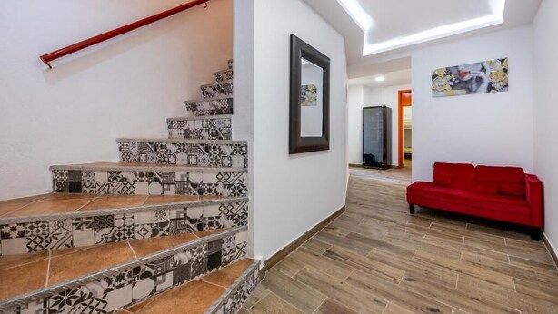 Un escalier orné de carreaux décoratifs, un canapé rouge et un tableau encadré accroché au mur.