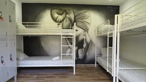 Une chambre avec des lits superposés, une fresque murale et une armoire.