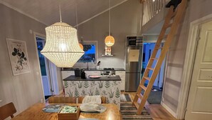 Une cuisine moderne dotée d’un îlot central, d’une table à manger en bois avec des chaises, et d’un escalier menant à un étage supérieur.
