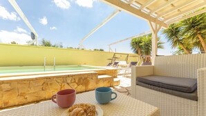 Ein Poolbereich mit einer Steinmauer, Liegestühlen, einem Tisch und einer Platte mit Croissants sowie einer blauen Tasse.