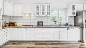 Een moderne keuken met witte kasten, een roestvrijstalen koelkast en een raam dat natuurlijk licht binnenlaat.