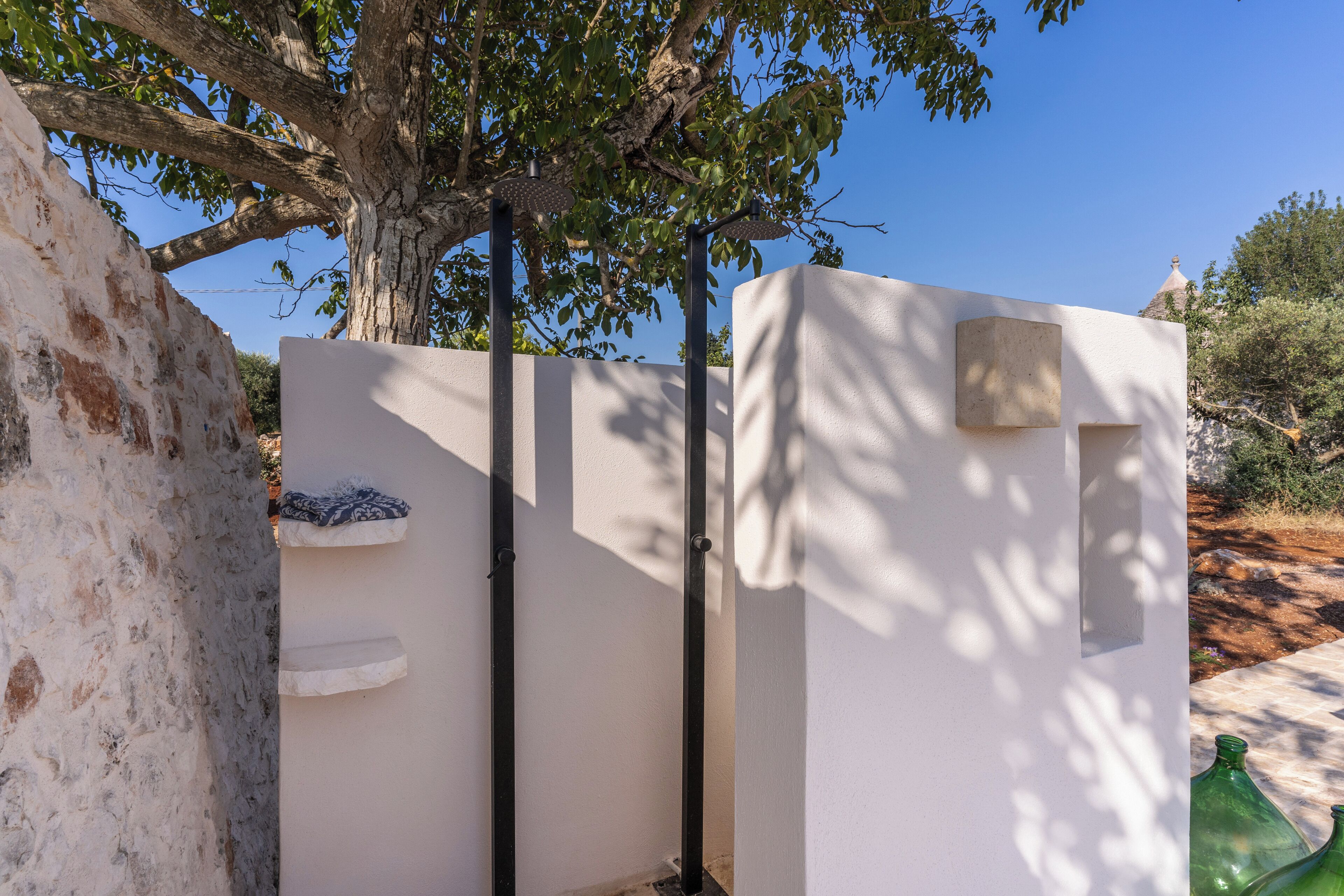 A white wall with a metal gate, a stone wall, and a tree in the background.
