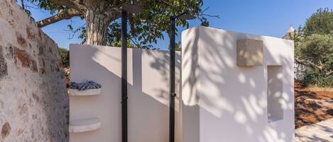 A white wall with a metal gate, a stone wall, and a tree in the background.