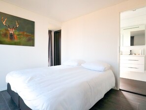 Relax in a serene space with a large bed, a wardrobe, and a beautiful painting of a deer above.