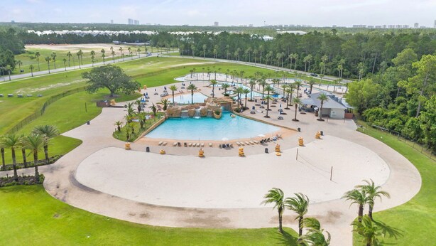 A large outdoor swimming pool with a waterfall feature, surrounded by palm trees and lounge chairs. - 🌊Incredible Location and Amenities-The Wharf 403🌊 (Orange Beach)