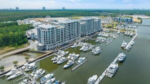 A marina with multiple boats docked, a large hotel building with multiple floors, and a Ferris wheel in the background. - 🌊Incredible Location and Amenities-The Wharf 403🌊 (Orange Beach)