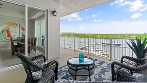 A balcony with wicker furniture, a glass table, and a view of boats on a body of water. - 🌊Incredible Location and Amenities-The Wharf 403🌊 (Orange Beach)