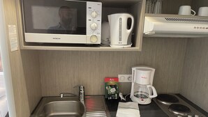 A compact kitchenette with a microwave, coffee maker, and a small sink. - Grand Studio Dans Résidence 3 Étoiles (Le Mée-sur-Seine)