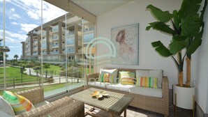 A modern apartment with large windows, wicker furniture, a view of a building, and a potted plant. - Los Flamencos 5004 - Two Bedroom Apartment, Sleeps 5 (Punta del moral)