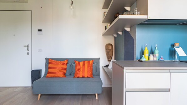 A modern living space with a grey sofa, orange cushions, a small table with bottles, and a blue accent wall.