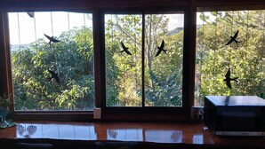 A room with a large window overlooking a lush garden. - Casa Monstera monteverde 

 (Monte Verde)