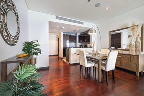 A modern dining area with a wooden table, white chairs, and a large mirror. - Anantara Palm Ocean View / Beach / Lagoon Pool (Dubai)