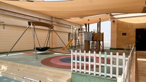 A children's play area with a swing set, slide, and climbing structure. - Anantara Palm Ocean View|Beach, Lagoons, Spa & Gym (Dubai)