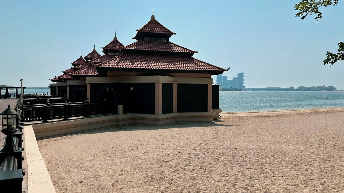 Un pavillon situé au bord de la plage, doté d ’un toit en tuiles, jouxtant une plage de sable et offrant une vue sur l’eau.