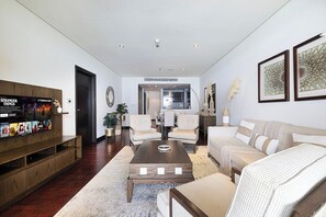 A modern living room with a wooden entertainment unit, a sofa, a coffee table, and a dining area in the background. - Anantara Palm Ocean View|Beach, Lagoons, Spa & Gym (Dubai)