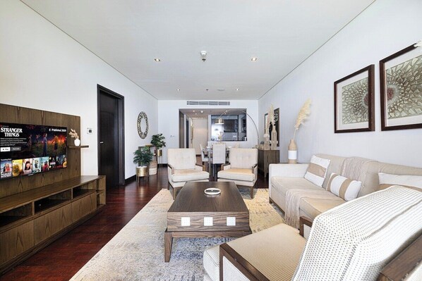 A modern living room with a wooden entertainment unit, a sofa, a coffee table, and a dining area in the background.