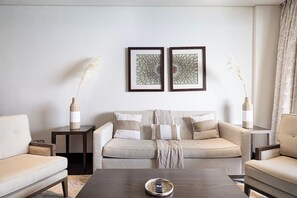 Una sala de estar con un sofá, dos mesas auxiliares y una mesa de centro.