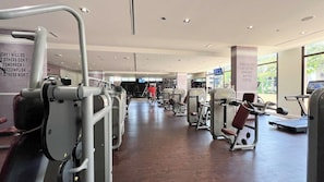 A gym with various exercise machines, a treadmill, and motivational posters on the walls.