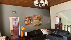 A living room with a dark leather sofa, a patterned rug, and wall art.