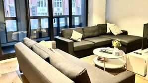 Una sala de estar moderna con un sofá modular, una mesa de centro redonda y un televisor de pantalla plana.