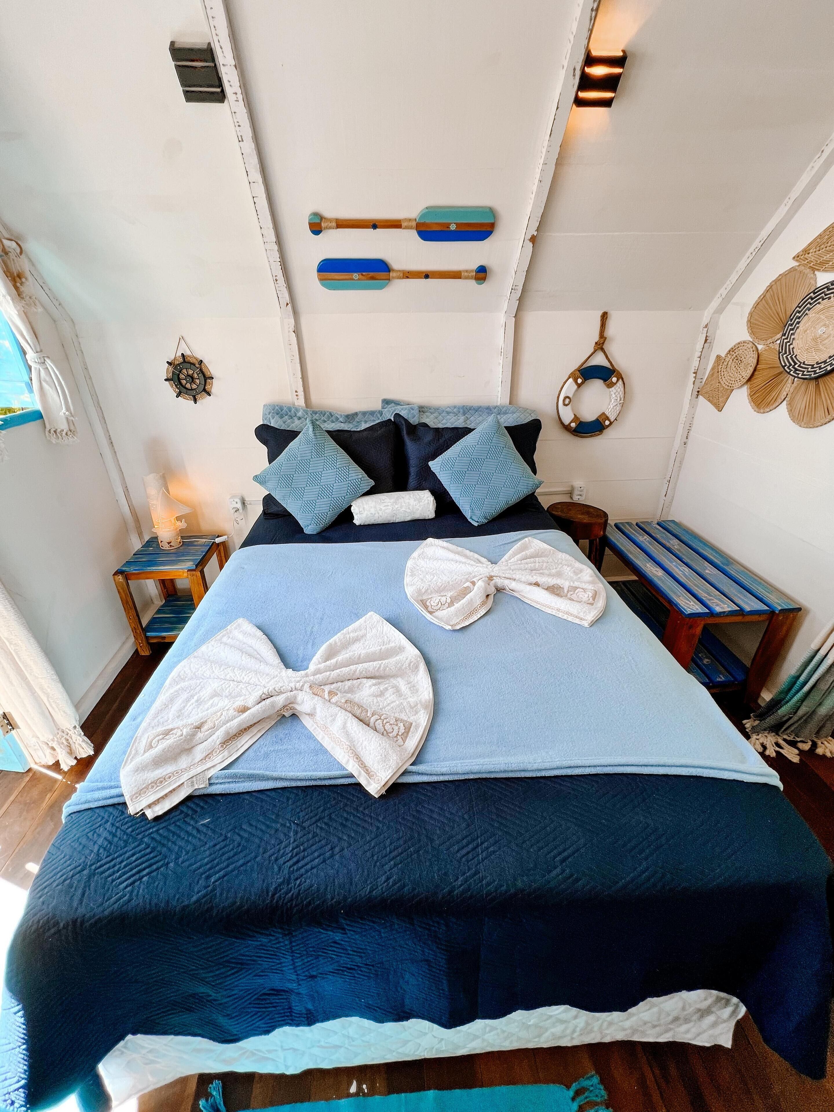 A bed with a blue and white bedspread, two towels, and a headboard with decorative elements.
