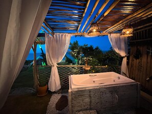 A bathroom with a bathtub, wooden ceiling, and curtains.