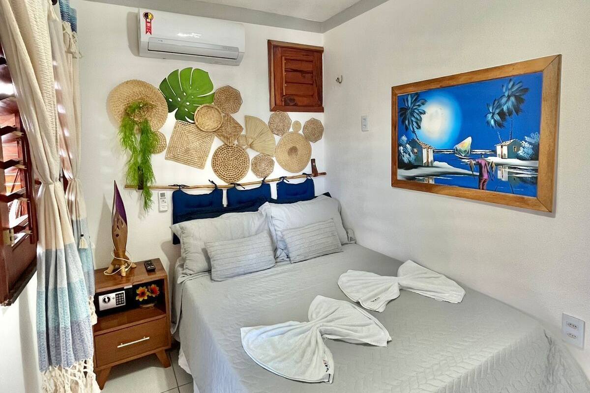 A bedroom with a bed, a nightstand, a painting, and a ceiling fan.