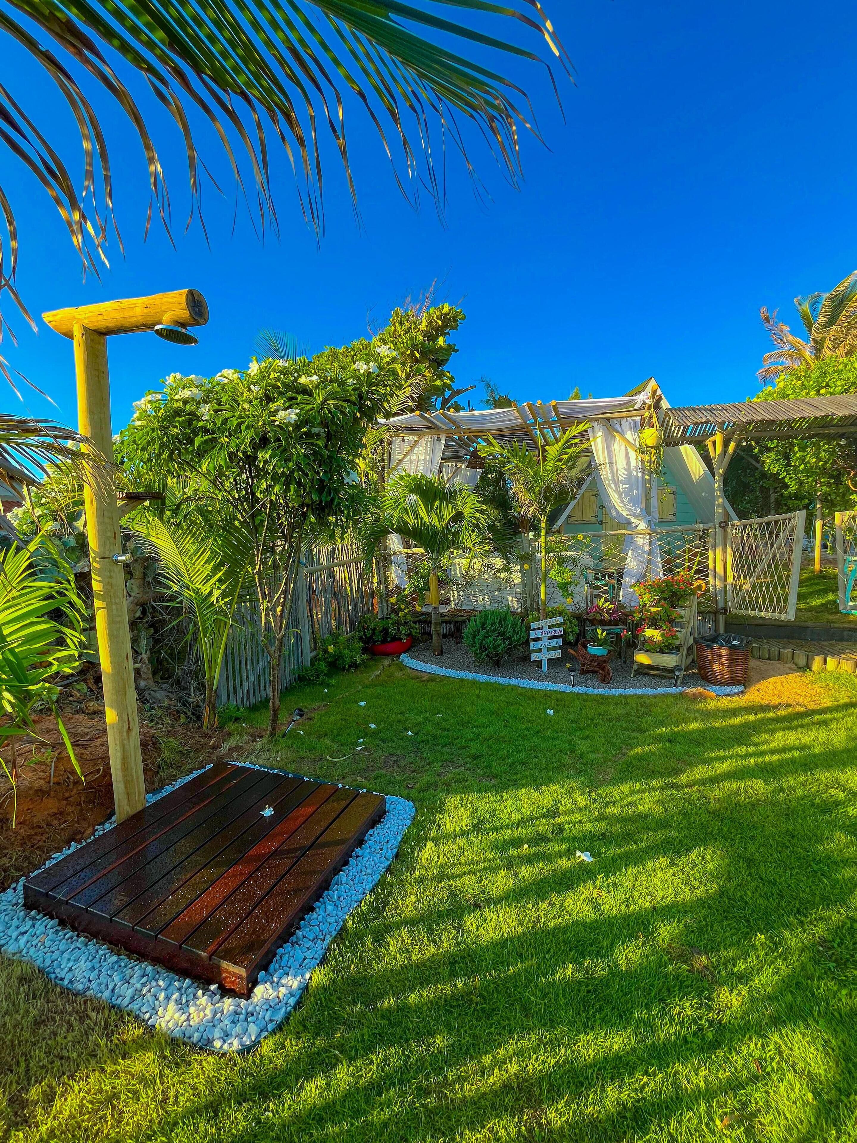 A well-maintained garden with a wooden pergola, a wooden deck, and a variety of plants and flowers.
