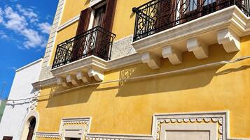 Un edificio giallo con balconi, una porta bianca e una finestra con persiane.