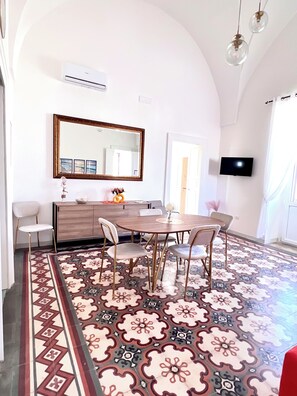 Enjoy a spacious room with a high arched ceiling, a dining table, and a large mirror, perfect for relaxation and entertainment.