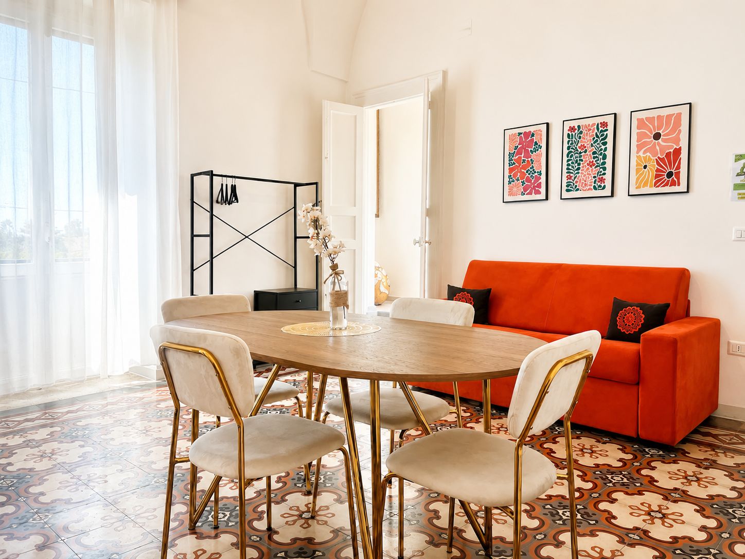 A dining area with a round table, four chairs, and a red sofa.