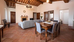 A spacious living area with a fireplace, a dining table with chairs, and a large sofa. - Villa Delizia, ArcenoRentalsClub, house in Chianti with garden, Concierge, Wifi (Villa A Sesta)